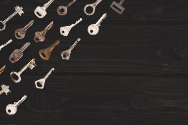 top view of different vintage keys on black table clipart