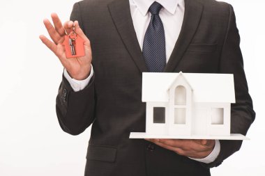 cropped image of man holding maquette of house with key isolated on white clipart