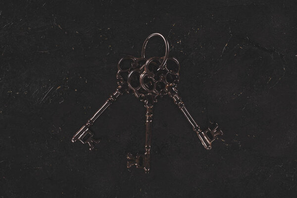вид сверху на старую металлическую связку ключей на черном столе
