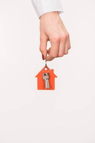 cropped image of female hand holding key from house isolated on white