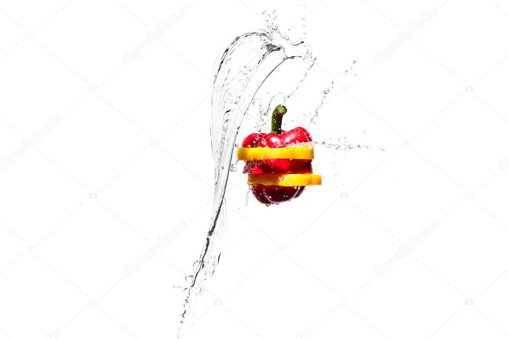 red and yellow bell pepper slices in water splashes isolated on white