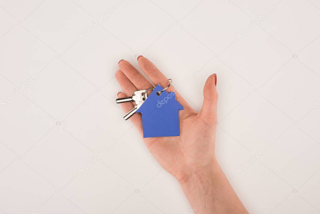 cropped image of female hand holding key from house isolated on white