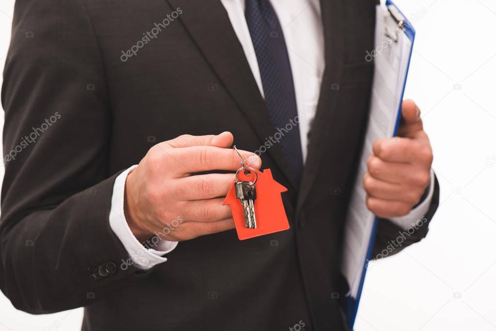 cropped image of man holding contract with key from house isolated on white