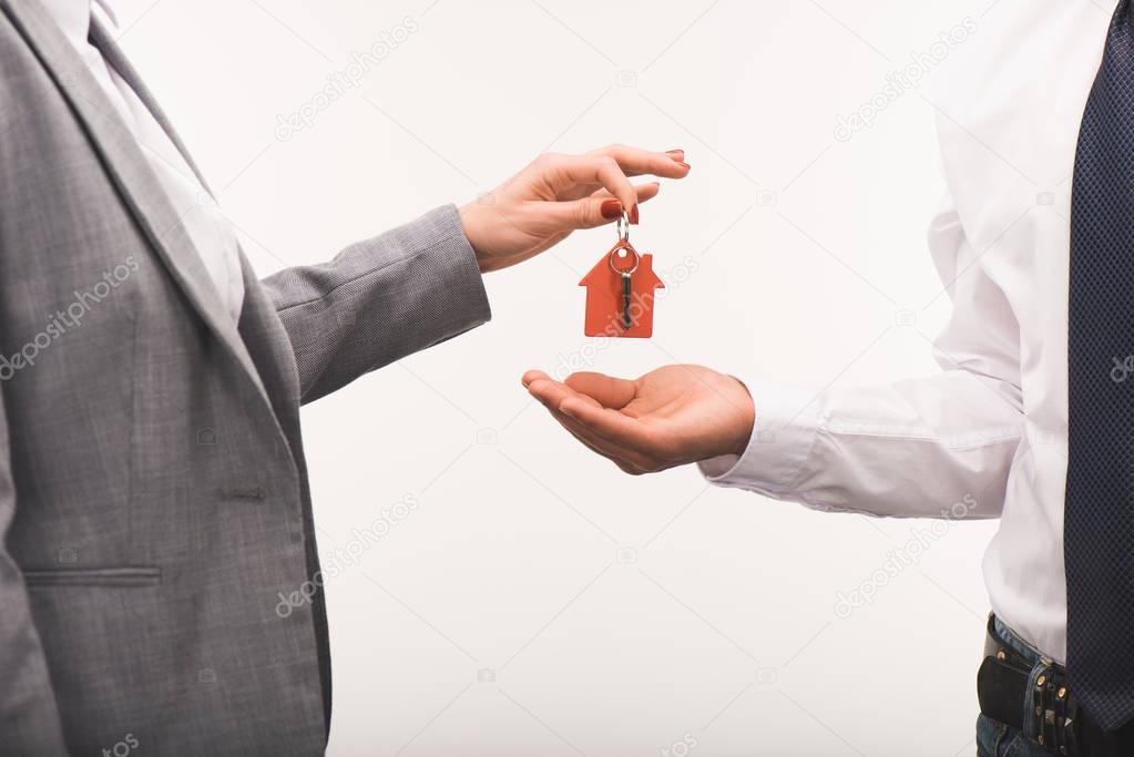cropped image of woman giving key from house to man isolated on white