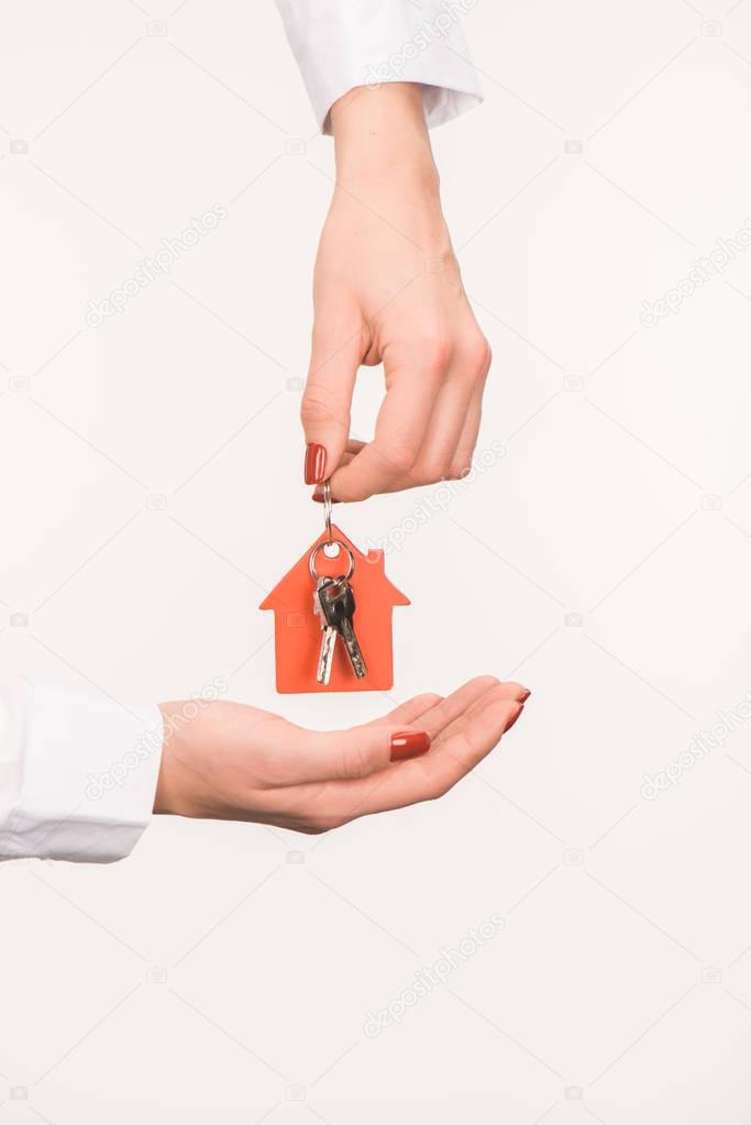 cropped image of female hands holding key from house isolated on white
