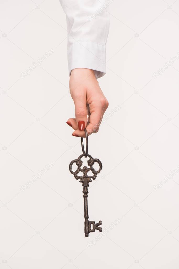 cropped image of female hand holding vintage key isolated on white