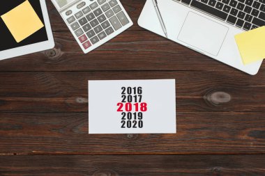 ahşap yüzey üzerinde dijital cihazlar, ofis malzemeleri ve 2018 takvim Üstten Görünüm