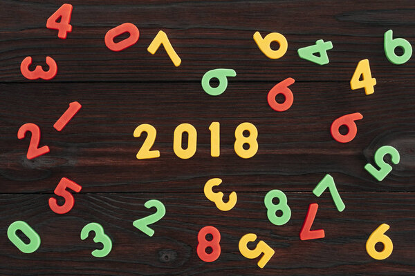 top view of colorful 2018 numbers on dark wooden surface