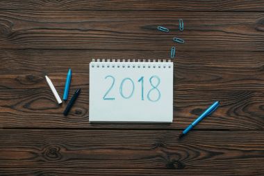 ahşap masa üzerinde 2018 ile düzenlenmiş defter, kalem, klipler ve kalem Üstten Görünüm