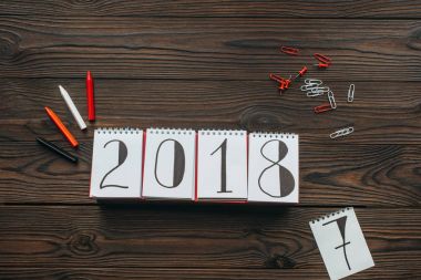 düz lay 2018 takvim, kalemler, düzenlenmesi ile iğne ve koyu ahşap masa üzerinde küçük resimleri