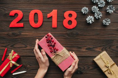 kırpılan tutan kadın görüntüsünü çam eksilerini ve çevresinde 2018 ahşap masa üzerinde elleriyle hediye sarılı