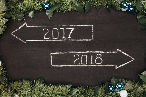 top view of 2017, 2018 year signs with christmas decorations around on dark wooden surface