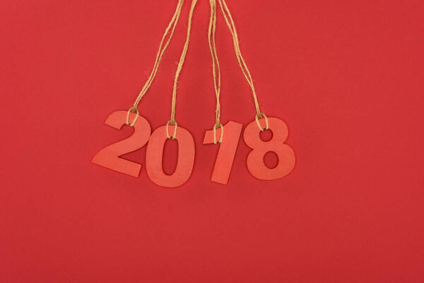 close up view of 2018 year sign hanging on strings isolated on red