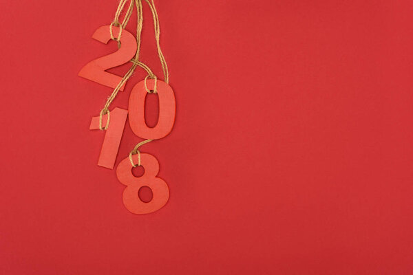 close up view of 2018 year sign hanging on strings isolated on red