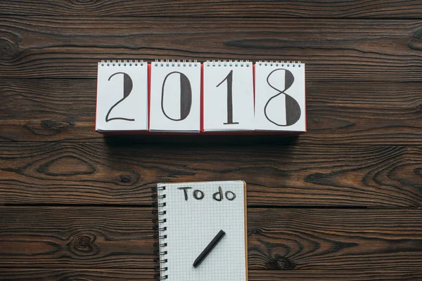 2018年日历和笔记本的顶部视图 在木制桌面上做刻字 — 图库照片