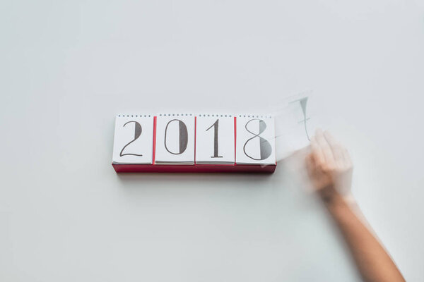 cropped shot of woman tearing calendar paper of 2018 year isolated on white