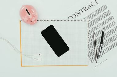 smartphone ile boş perde üstten görünüm üstünde defter, kalem ve kumbara beyaz ile sözleşme 