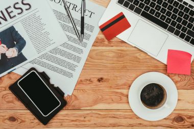ahşap masa üzerinde akıllı telefon, sözleşme, gazete, kredi kartı ve dizüstü Üstten Görünüm 