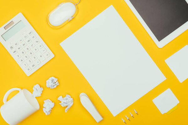 top view of blank sheet of paper, crumpled papers, notes, calculator and cup isolated on yellow