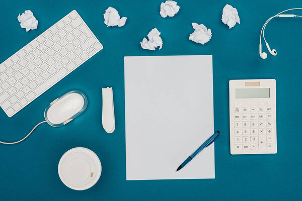 top view of blank sheet of paper with pen, calculator, computer mouse and keyboard on blue