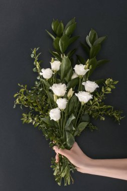 cropped image of female hand holding bouquet with eustoma and branches over black background  clipart