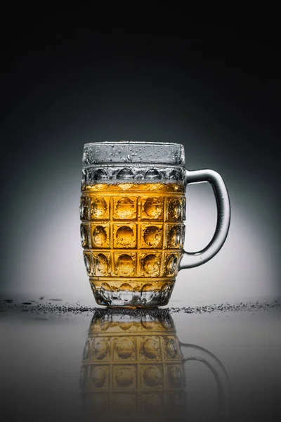 glass with light cold beer on gray reflecting surface