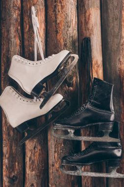 pairs of white and black skates hanging on wooden wall clipart