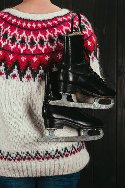 обрезанный образ женщины, стоящей с черными коньками на плече
