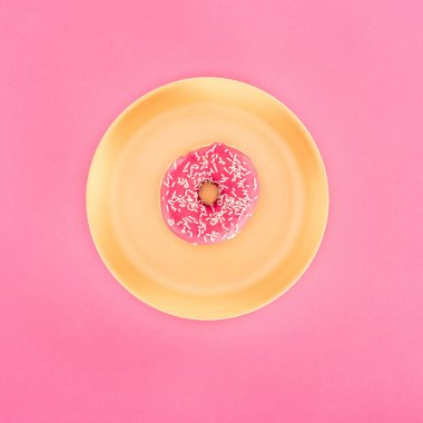 top view of pink glazed doughnut on yellow plate isolated on pink clipart
