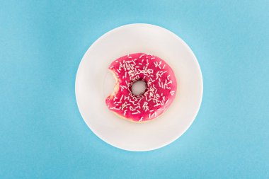 top view of bitten pink glazed doughnut on plate clipart
