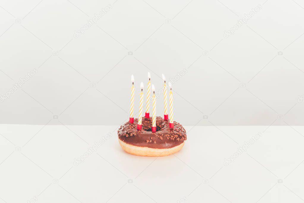 delicious glazed doughnut with birthday candles on white table