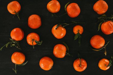 siyah ahşap yüzeye yapraklarla mandalina, düzenlemenin düz lay