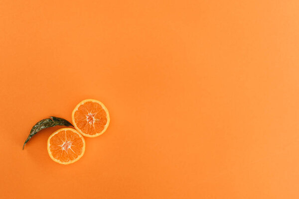 top view of pieces of orange and leaf isolated on orange