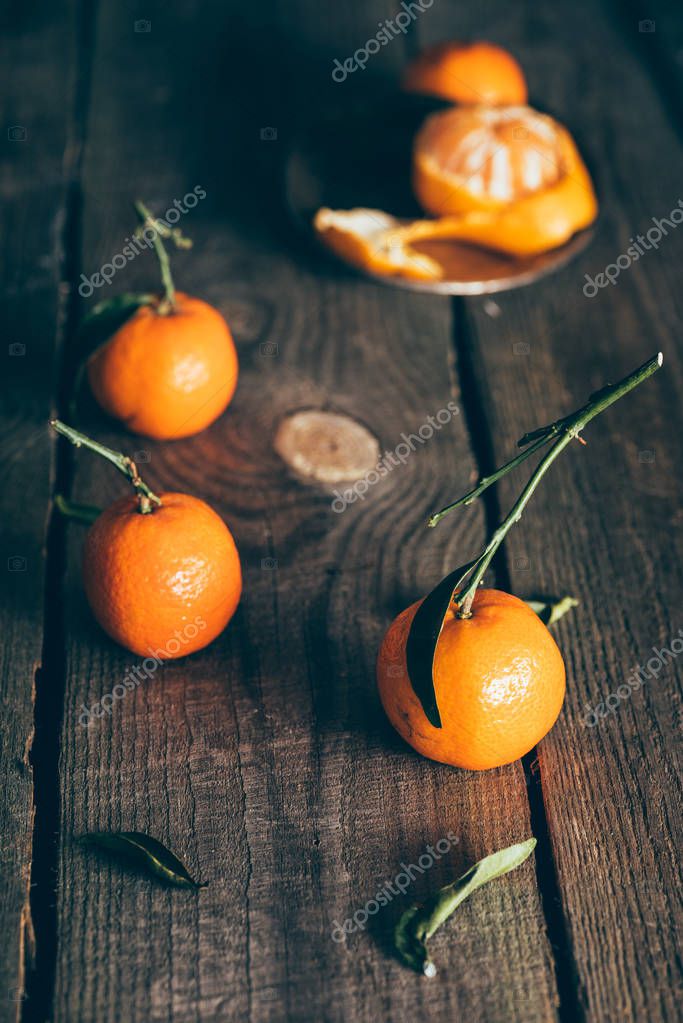 Close up view of ripe mandarins with leaves on wooden tabletop