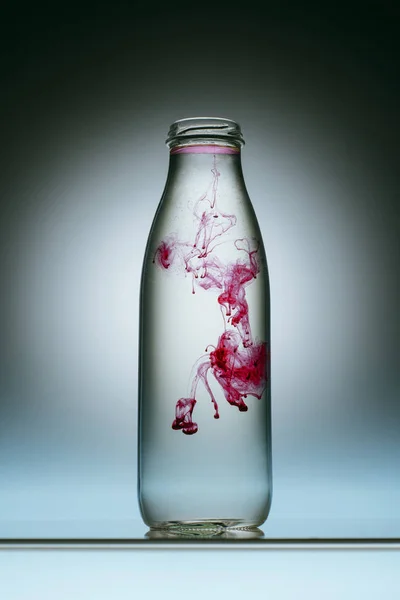 水のボトルにピンクの塗料スプラッシュのクローズ アップ表示 — ストック写真
