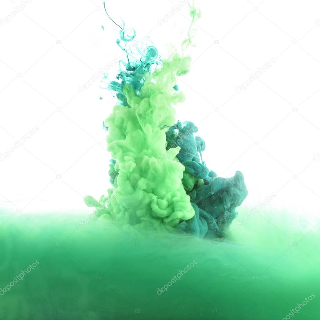 close up view of mixing of green and blue paint splashes isolated on white