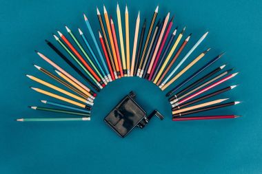 Top view of composition of colorful pencils and sharpener isolated on blue background clipart