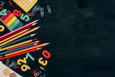 Top view of composition of colorful school supplies isolated on dark board background clipart