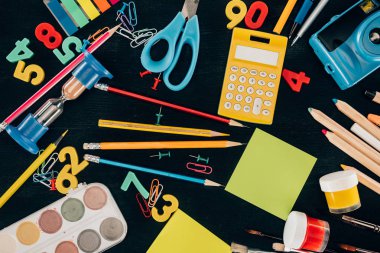 Top view of composition of colorful school supplies isolated on dark board background clipart