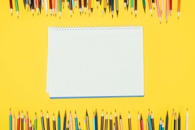 Renkli kalemler defter Sarı zemin üzerine izole çerçevenin Üstten Görünüm