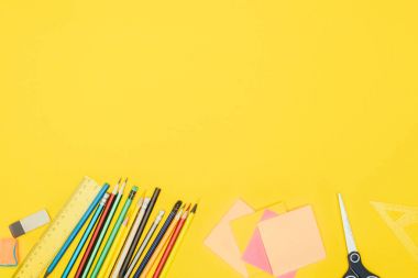 Top view of composition of colorful school supplies isolated on yellow background