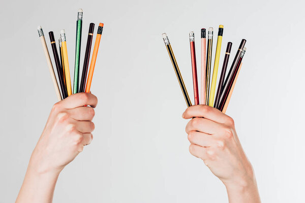 Крупный план женских рук с красочными карандашами на белом фоне
