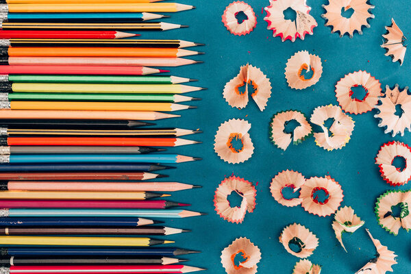 Top view of composition of colorful pencils and cuttings isolated on blue background