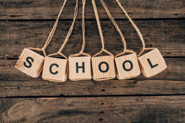 Вид сверху кубиков с надписью "школа" на деревянном фоне
