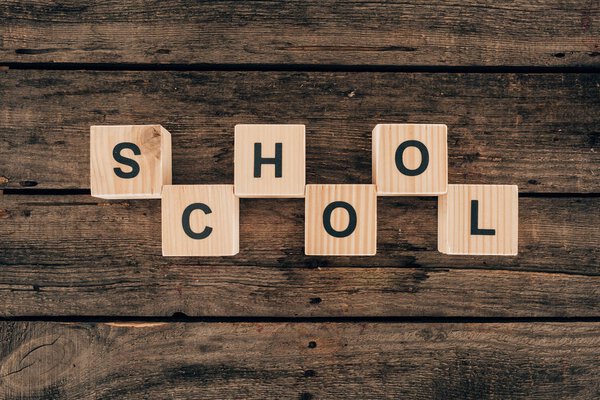 Вид сверху кубиков с надписью "школа" на деревянном фоне
