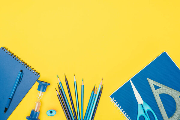 Top view of composition of colorful school supplies isolated on yellow background