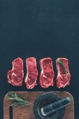 pohled shora syrové steaky v řádku s kořením na dřevěné desce
