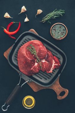 top view of raw steak on grill pan with various spices around clipart
