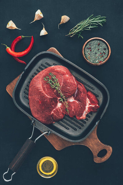 top view of raw steak on grill pan with various spices around