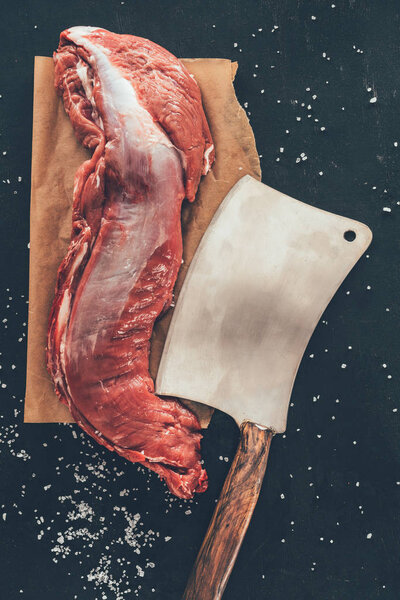 top view of raw pork meat with cleaver on wooden board